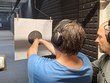 P. Šopa na střelnici trénuje střelbu na terč pod odborným dohledem bývalého policisty p. Vaňka. Instruktor mu pomáhá se správným postojem, mířením a bezpečnou manipulací se zbraní
