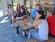 Na fotografii sedí skupina klientů a pracovnic u venkovního stolu před KFC. Společně odpočívají, povídají si. Panuje příjemná letní atmosféra. Zleva: p. Ilona (dobrovolnice), p. Spáčil, p. Cabajová, DiS., p. Špinarová, DiS., p. Vanko, p. Neckářová, p. Šulerová
