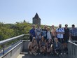 Společná fotografie na vyhlídce u hradu Zvíkov. V pozadí je kamenná věž, lesy a vodní hladina