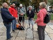 Na fotografii zleva: p. Vondra, p. Kotrba, p. Svoboda, p. Vlašín, p. Spáčil, p. Dvořáková – stojící na náměstí kolem několika bílých holí, které mají položené uprostřed před sebou. V pozadí jsou stromy a historické domy